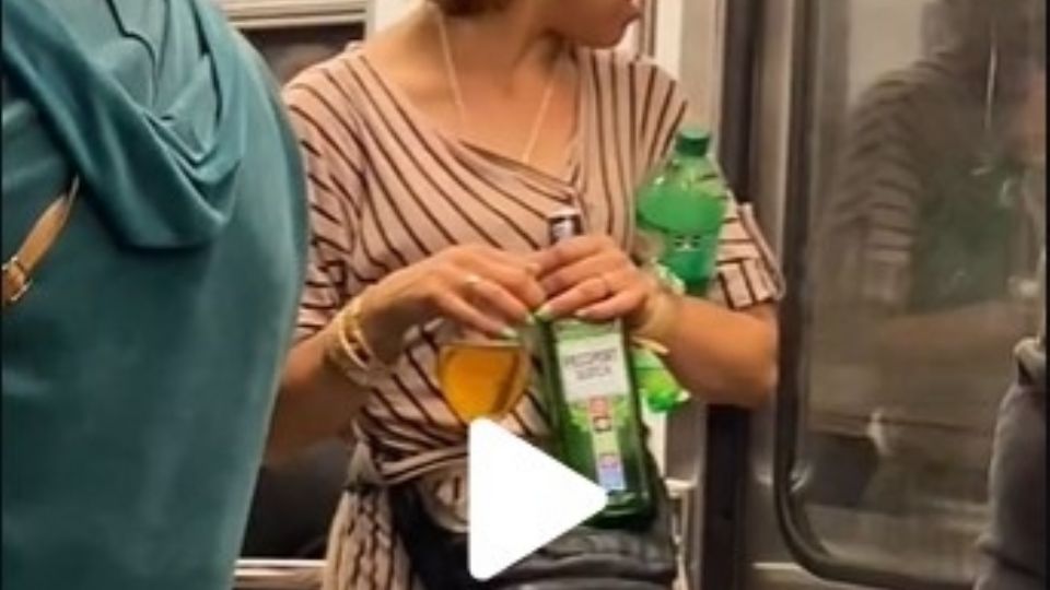 Una mujer es vista con una botella de whisky, copa y refresco, en el Metro de la Ciudad de México